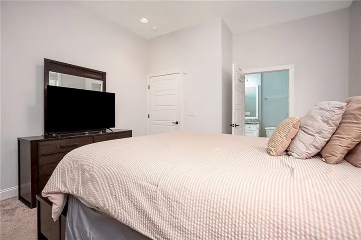 High ceilings and recessed lighting define this serene bedroom with direct en suite bathroom access.