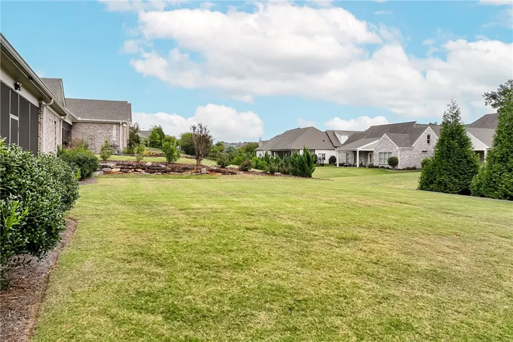 A spacious green lawn sits behind these brick homes under a blue sky.