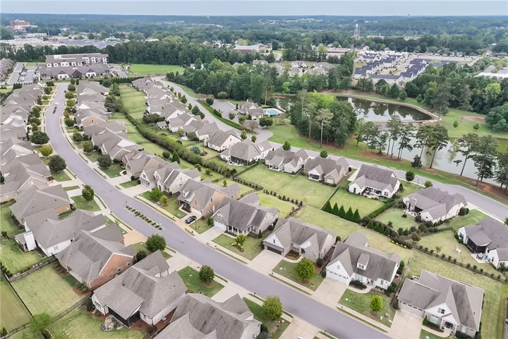 An aerial perspective showcases a neat residential neighborhood with manicured lawns and nearby community water features.