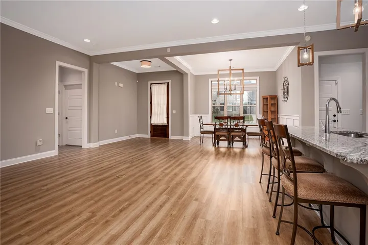 Warm wood-style flooring and crown molding define this open concept dining and living area.
