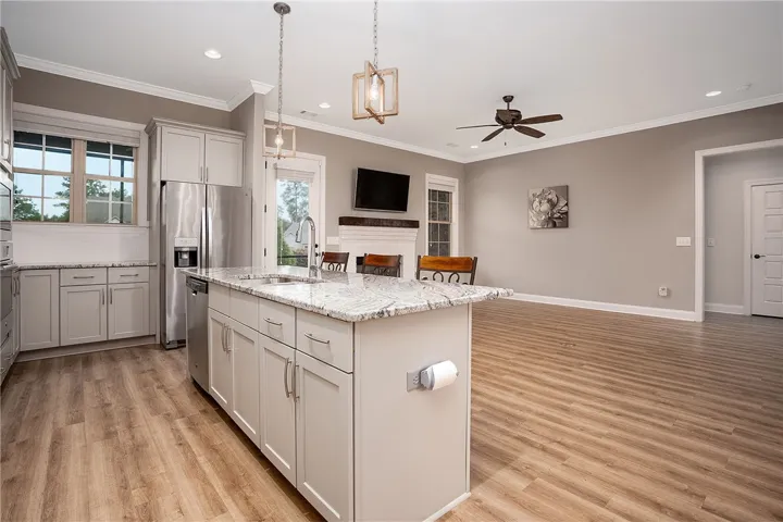 An open kitchen featuring granite countertops and a spacious island transitions into the living area.