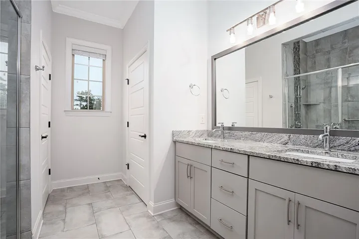 A spacious vanity with granite countertops and tiled flooring defines this modern bathroom layout.