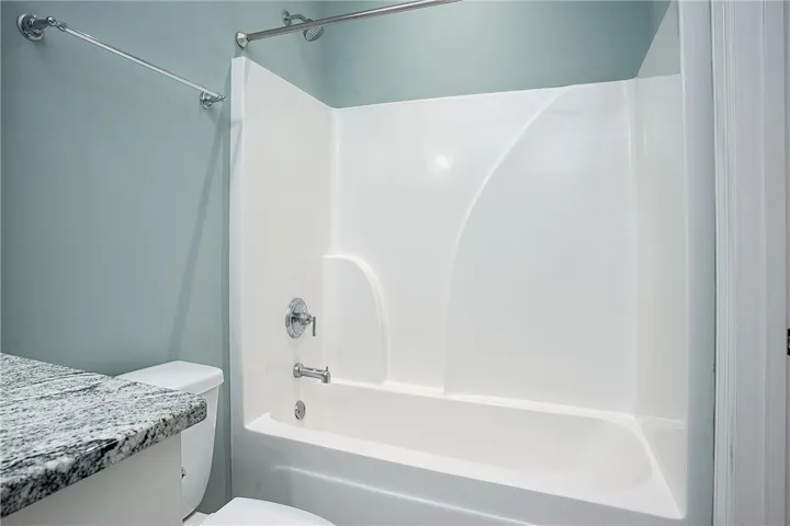 Polished granite counters and a clean tub shower combination create a functional bathroom design.