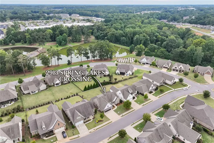 An aerial perspective showcases a neat neighborhood cul-de-sac bordered by mature trees and a tranquil pond.