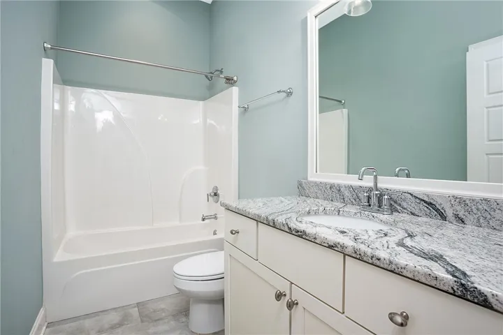 Polished granite countertops complement the clean white cabinetry and classic tub in this bathroom.