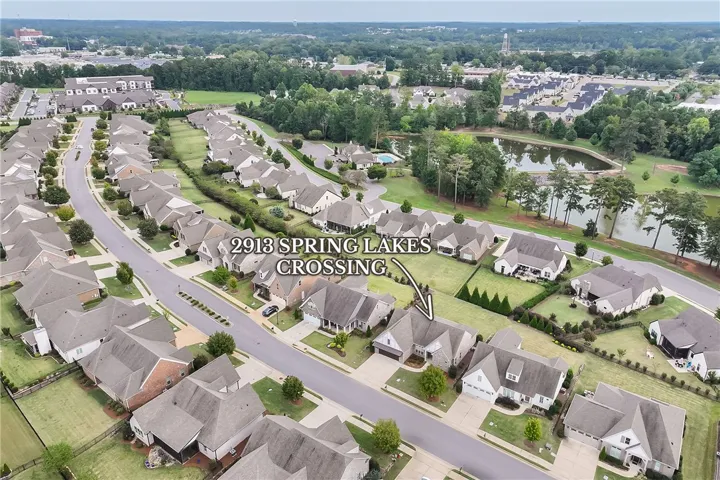 An aerial perspective showcases a manicured suburban neighborhood nestled alongside tranquil water features.