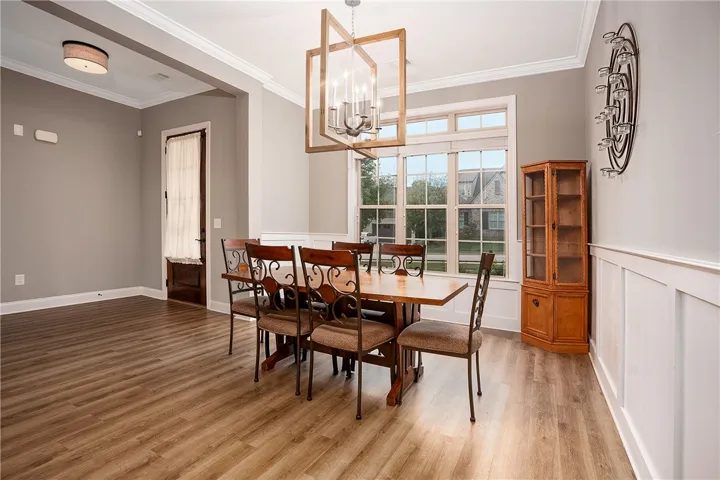 An elegant dining space features rich wood flooring, classic wainscoting, and a large multi-pane window.