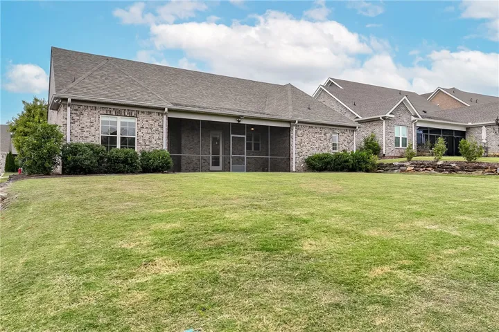 An expansive green lawn stretches behind this classic brick home featuring a screened rear porch.