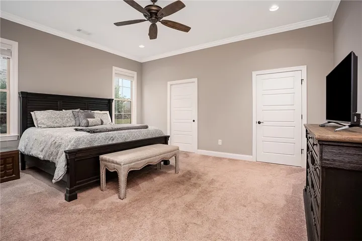 Thick crown molding frames the recessed lighting and plush carpeting in this bedroom.