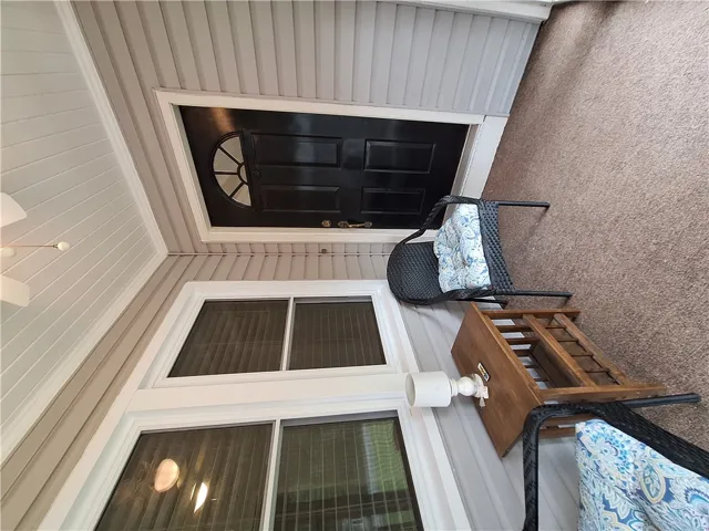 An inviting entryway porch features durable siding, a dark entry door, and carpeted flooring.