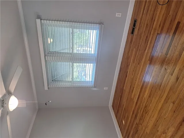 Rich hardwood floors and classic crown molding frame a bright window in this versatile space.