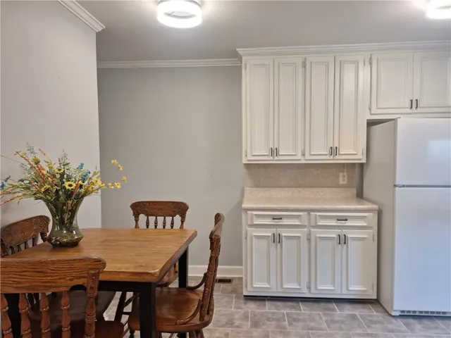 Crisp crown molding accents this dining area featuring neutral tile flooring and classic white cabinetry.