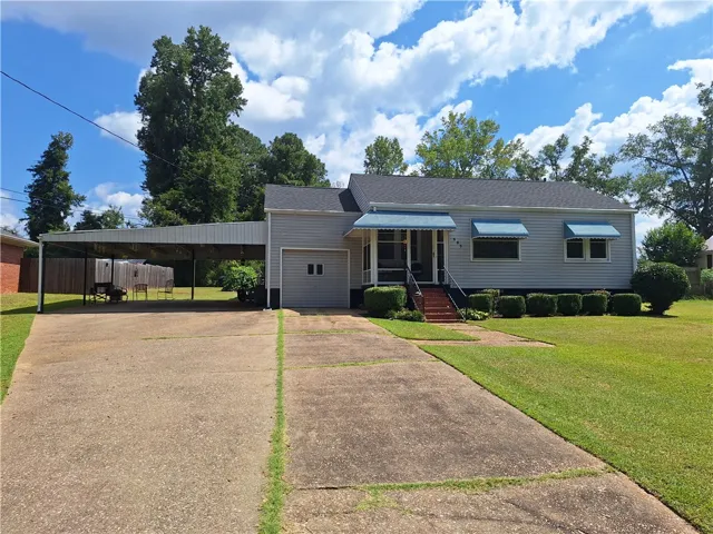 Classic siding exterior highlights this charming home featuring an attached carport and a paved driveway.