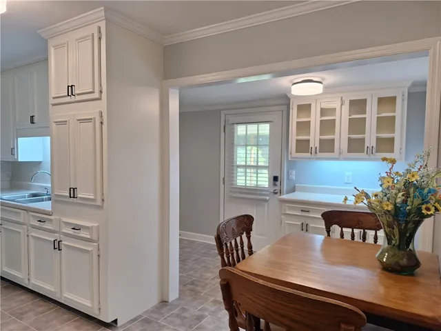 Crisp white cabinetry and classic crown molding frame this functional dining and kitchen space.