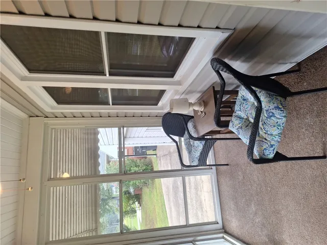A screened porch features carpeted flooring and large windows looking out to the yard.