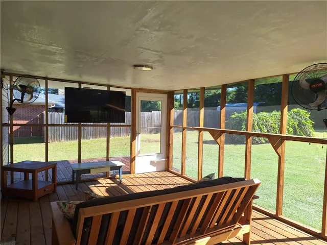 Floor-to-ceiling screens enclose a wood-planked porch overlooking a spacious yard.