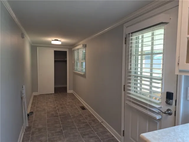 Tiled flooring, clean crown molding, and windowed door access define this practical transition area.