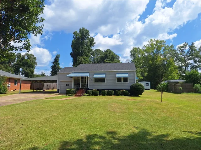 Classic vinyl siding and protective window awnings define this charming single-story ranch home.