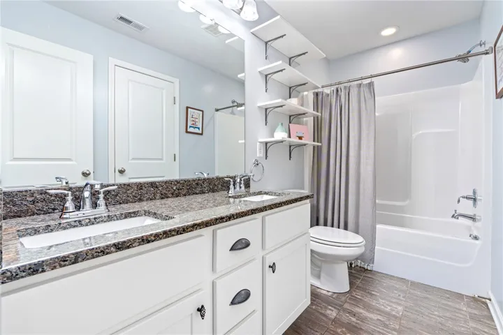 Polished granite countertops complement a spacious double vanity in this well-appointed bathroom.