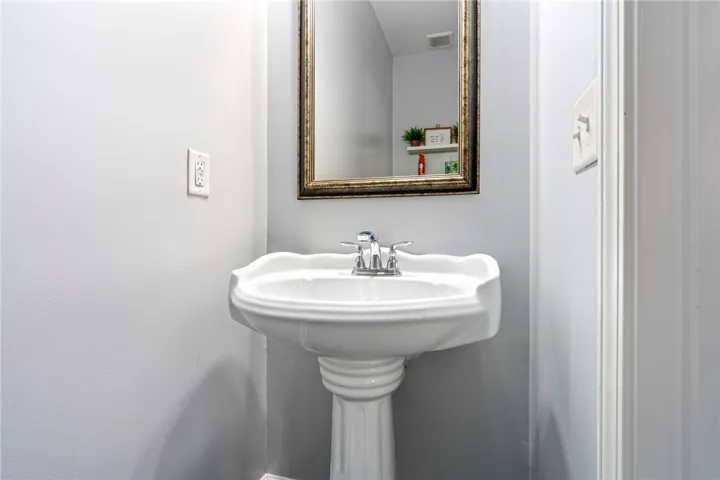 A classic pedestal sink sits beneath a framed mirror in this clean powder room.
