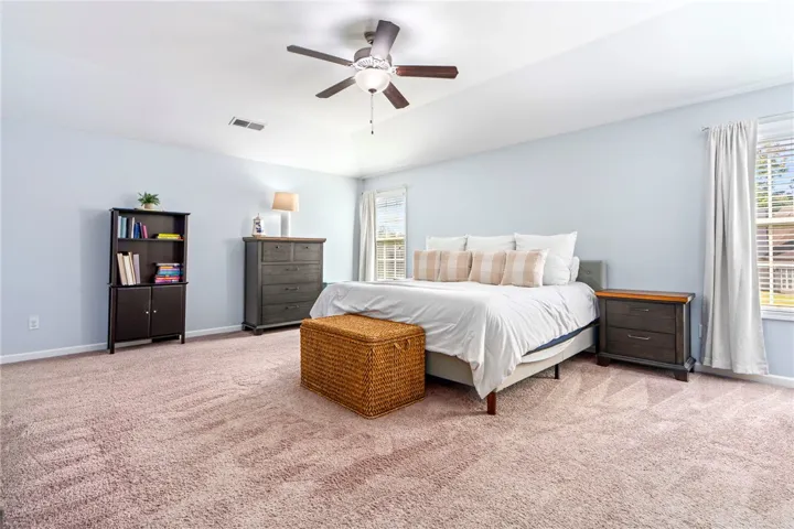 A spacious bedroom displays comfortable plush carpeting and high-set tray ceilings.