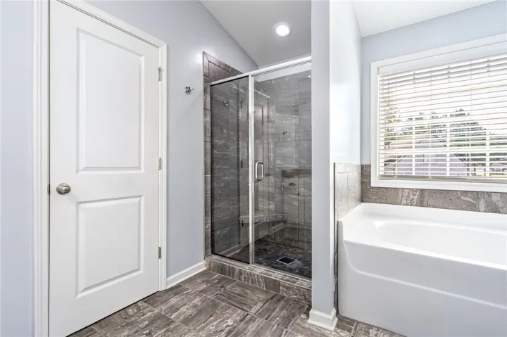 An inviting bathroom displays a modern tiled walk-in shower alongside a deep soaking tub.