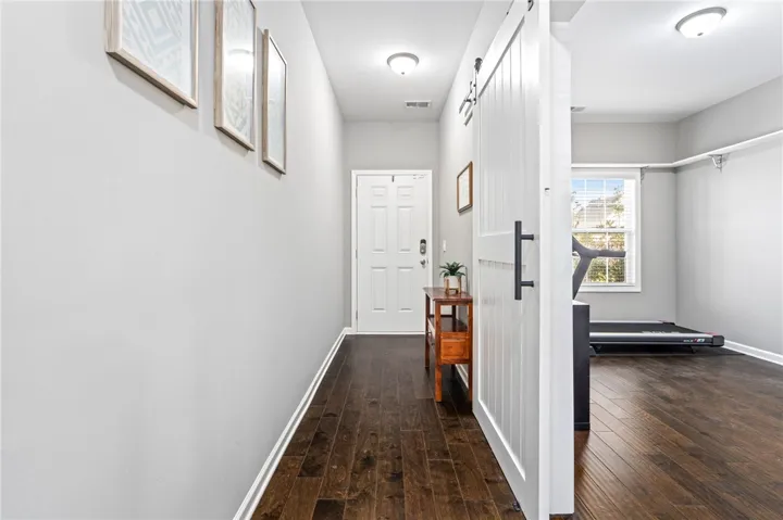 Rich hardwood flooring anchors the inviting entryway and adjacent multipurpose room.