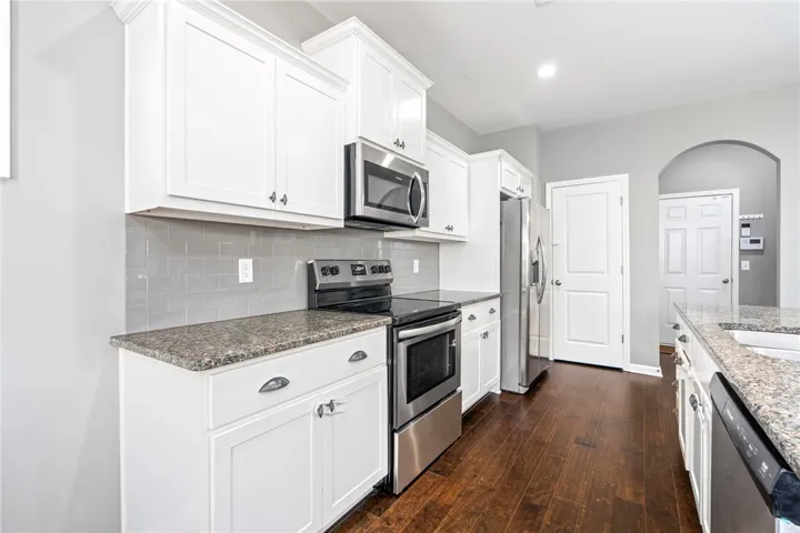 Gleaming hardwood floors complement granite countertops and classic white cabinetry in this functional workspace.