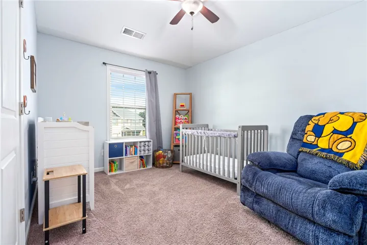 A quiet bedroom retreat featuring neutral wall tones, soft carpeting, and a bright classic window.