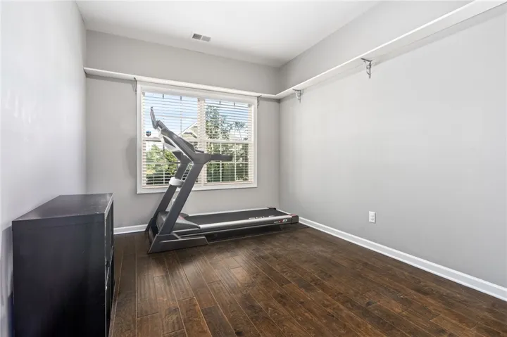 Rich hardwood flooring anchors this versatile space, highlighted by a large window and high ceilings.