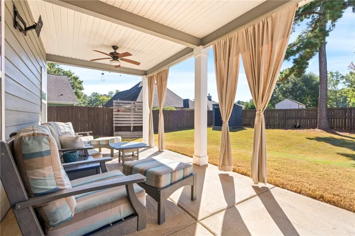 A covered concrete patio overlooks the spacious fenced backyard.