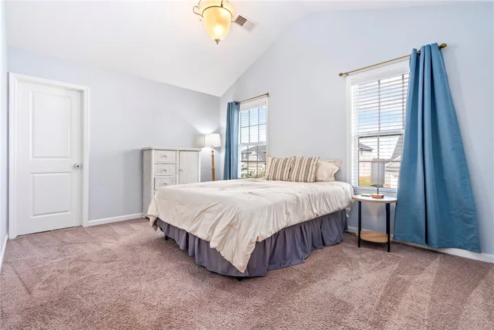 Vaulted ceilings and plush carpeting define this inviting secondary bedroom with dual windows.