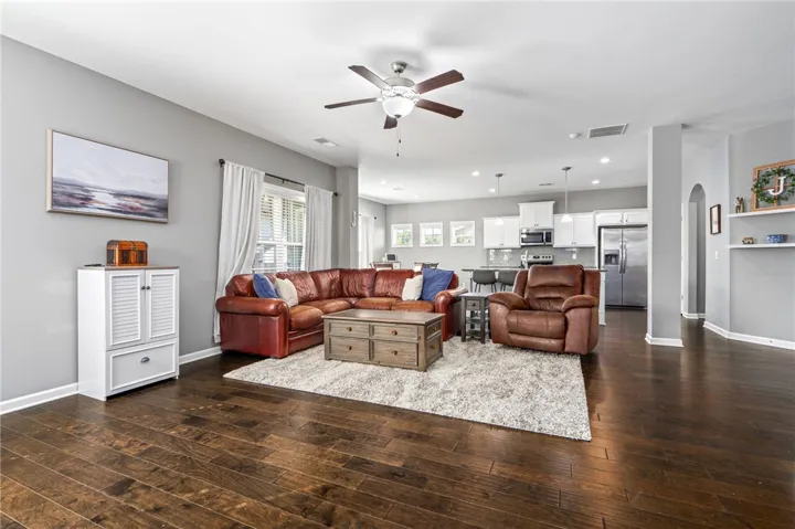 Gleaming hardwood floors run through a spacious, open living area connected directly to the kitchen.