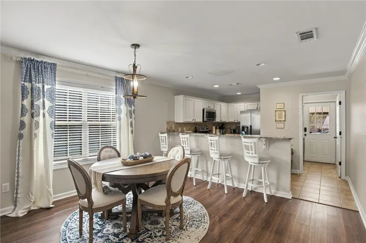 An open floor plan connects the dining area to a modern kitchen with crown molding.