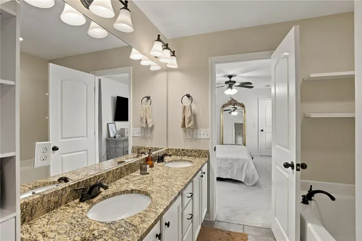 A spacious double vanity features granite countertops alongside an integrated soaking tub.