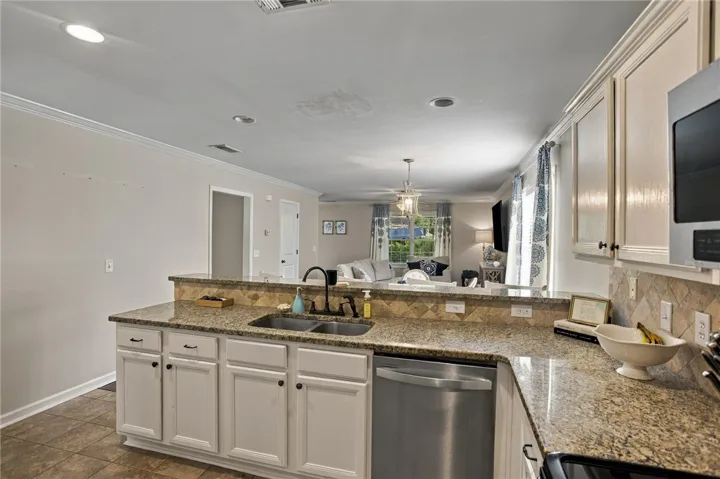 Granite countertops and white cabinetry define this functional kitchen overlooking the living space.