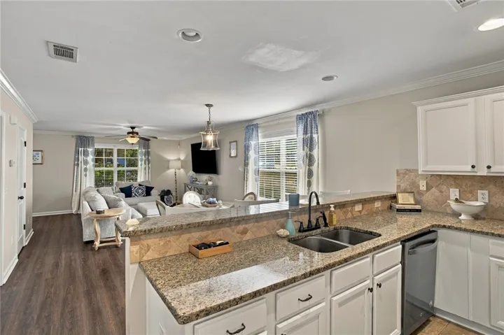 Granite countertops and white cabinetry anchor this seamlessly integrated culinary and living space.