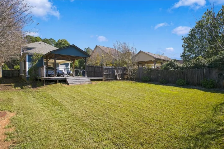 A spacious green lawn stretches out behind the home, bordered by a wooden privacy fence.
