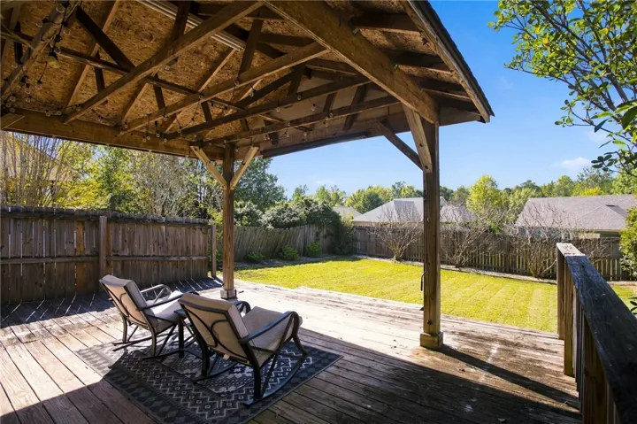 A spacious wooden deck with a vaulted shelter overlooks the grassy backyard.