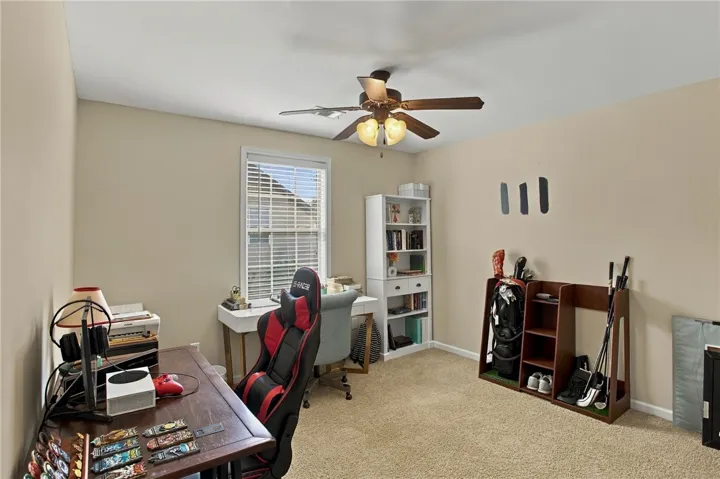 A well-lit secondary room features neutral walls, comfortable carpeting, and a large window.