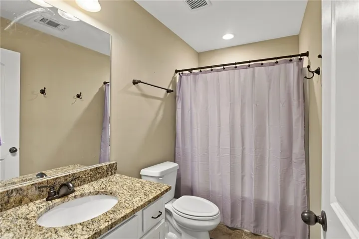 A classic bathroom featuring a neutral-toned vanity topped with granite counters.