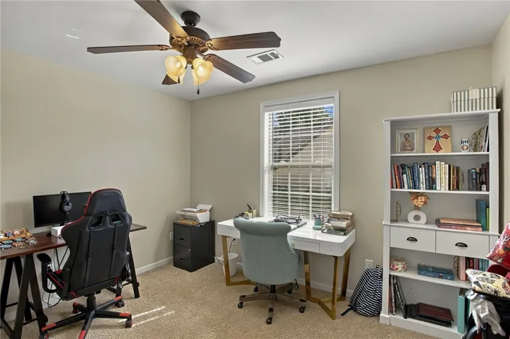 Natural light streams through a large window onto carpeted flooring in this versatile workspace.