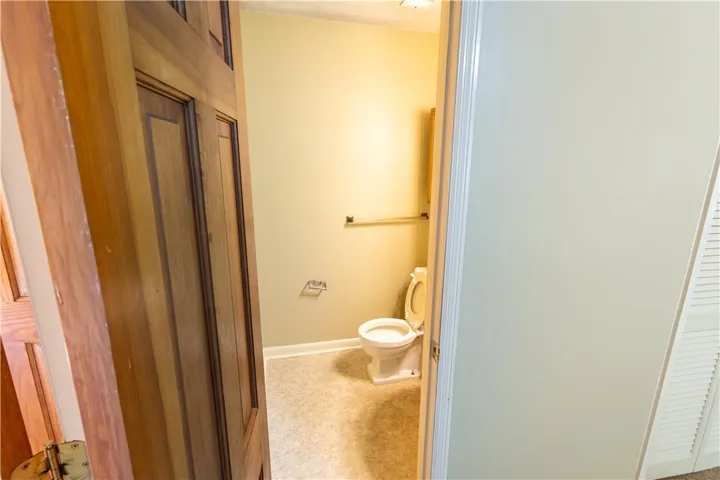 A classic six-panel wood door opens to reveal a clean half bath with durable vinyl flooring.