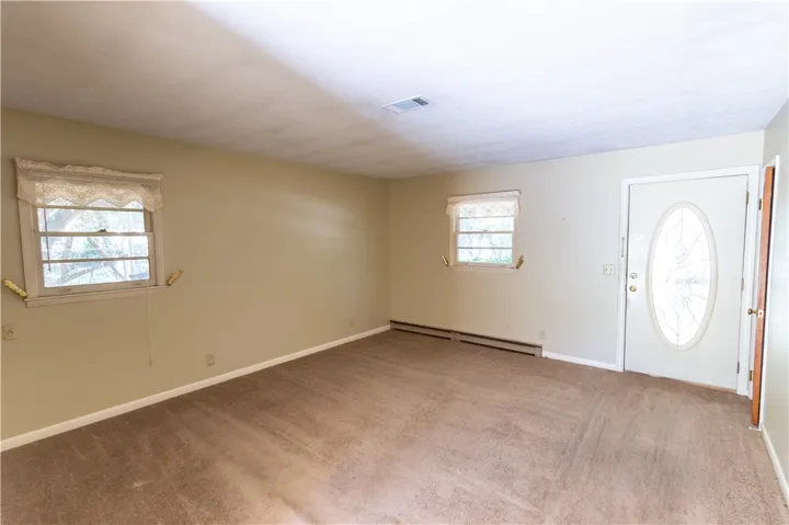 A classic entry door opens directly into a spacious living area finished with wall-to-wall carpeting.