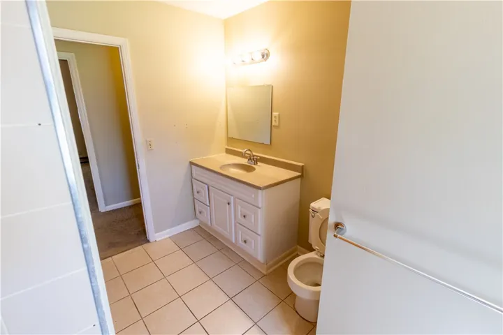 A classic single vanity pairs with neutral tile flooring in this functional bathroom layout.