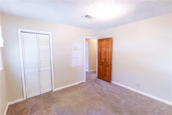 A classic six-panel wood door and louvered closet doors accent this carpeted bedroom space.
