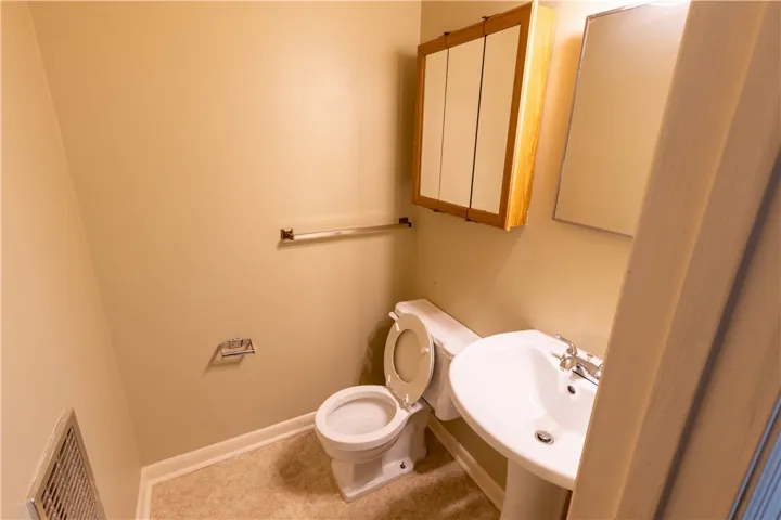 A functional half bath features a pedestal sink and practical built-in wall cabinets.