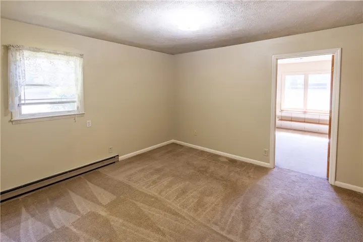 Plush carpeted flooring runs through this versatile space next to an adjacent sunroom.