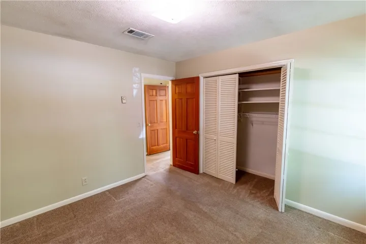 A spacious closet with built-in shelving sits adjacent to a classic wood-paneled door.