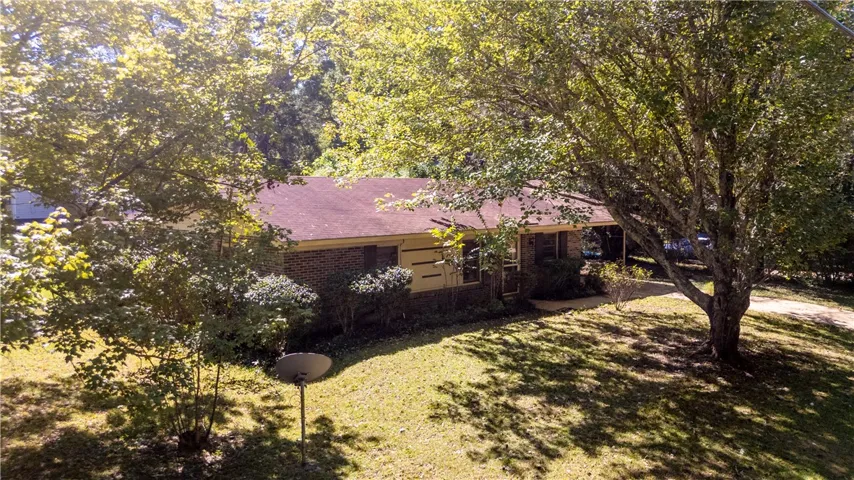 Mature trees frame this classic brick-front home featuring a low-maintenance metal roof.